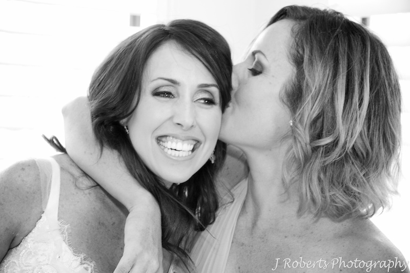 Sister kissing excited bride - wedding photography sydney